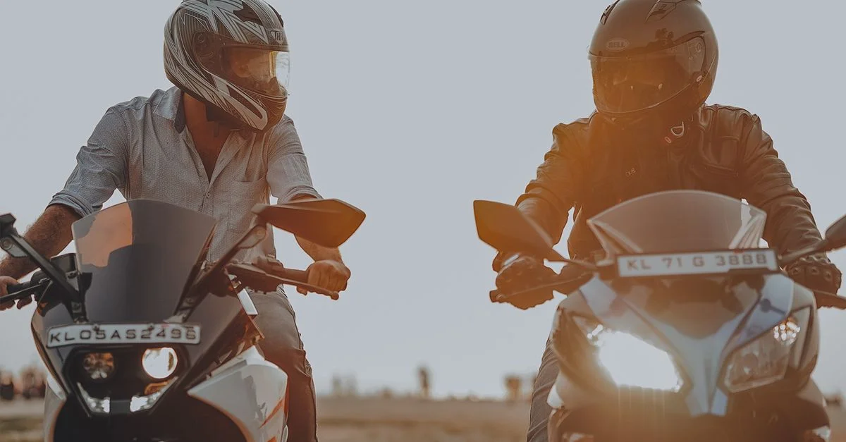 Deux hommes faisant de la moto avec des casques au coucher du soleil. Concept d'action et d'aventure en plein air.
