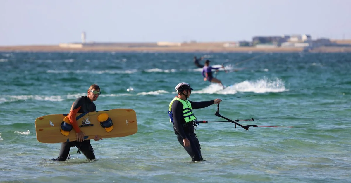 Deux kitesurfeurs s'engagent dans des sports nautiques palpitants sur la plage. Idéal pour des images d'action estivales.