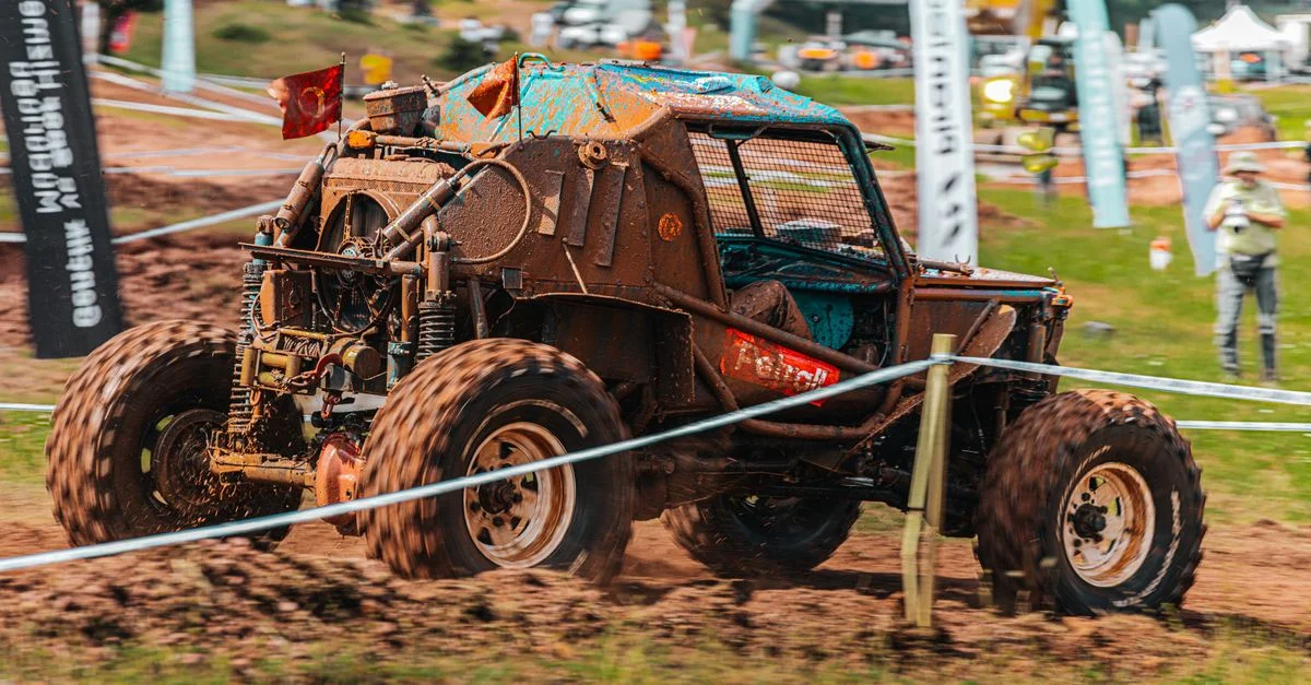 Scène de course tout-terrain intense avec un buggy robuste manœuvrant à travers un terrain boueux sur une piste.