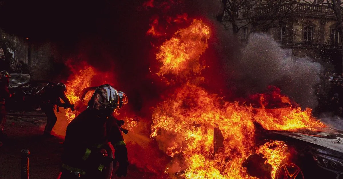 Image dramatique de pompiers intervenant sur un incendie de voiture flamboyant à Paris la nuit.